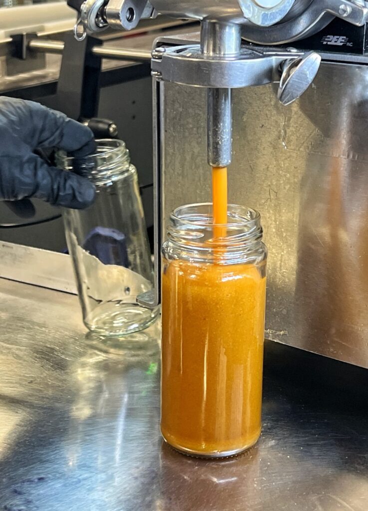 Amber syrup being filled into a jar on the Chaé production line
