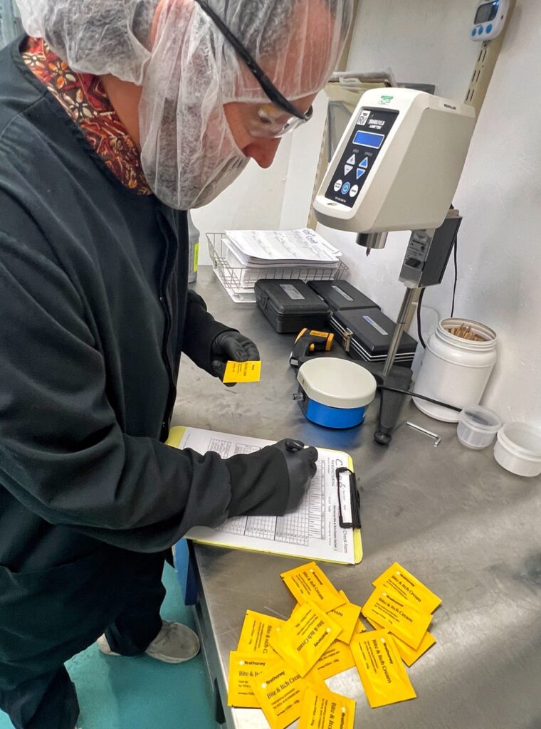 A Chaé technician recording batch data on a clipboard at the production equipment